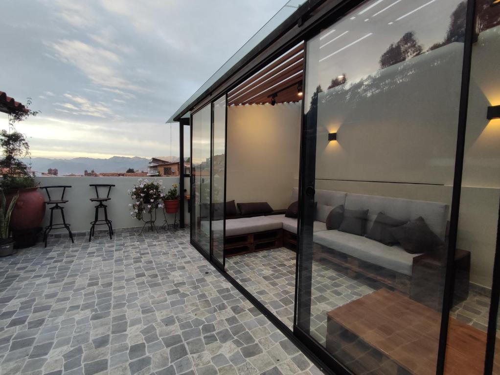 库斯科Casa Agustina的阳台设有玻璃墙,天井设有沙发