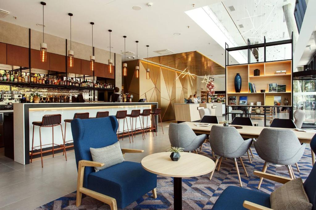 维尔纽斯维尔纽斯市中心万怡酒店的一间设有蓝色椅子的餐厅和一间酒吧