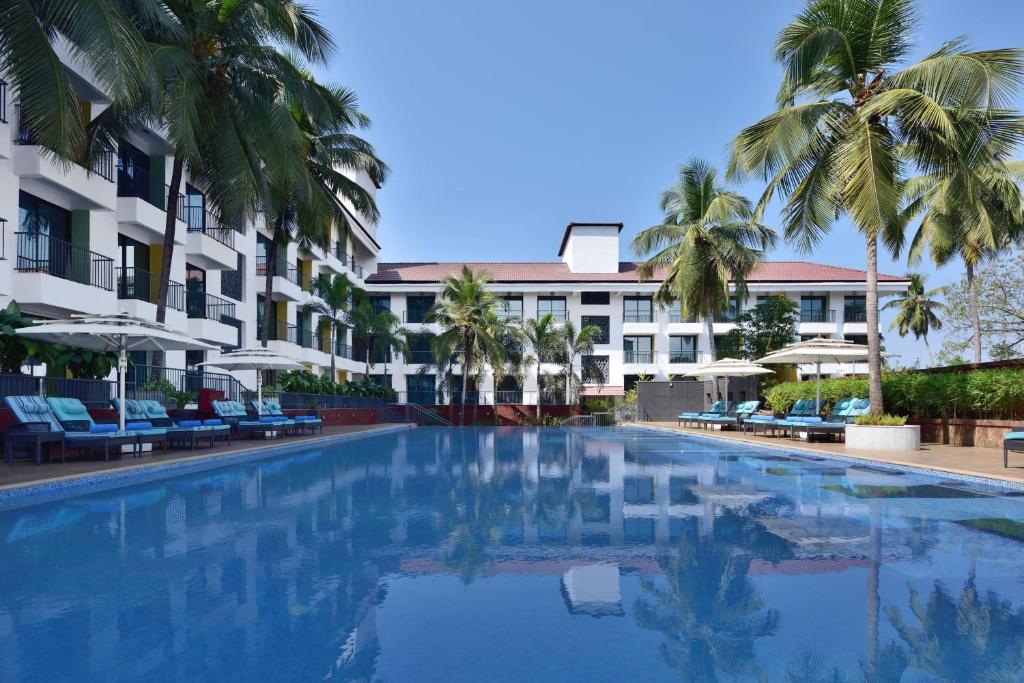 安君纳Fairfield by Marriott Goa Anjuna的一座棕榈树和建筑游泳池