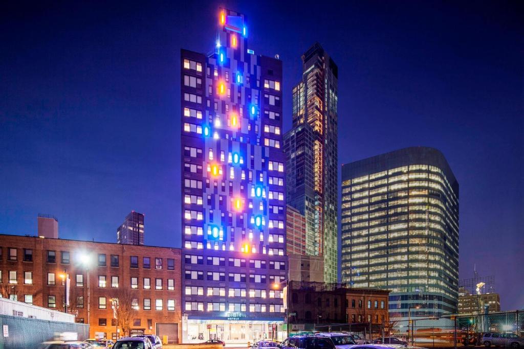 皇后区长岛市曼哈顿景观雅乐轩酒店的一座高大的建筑,上面有蓝色的灯光