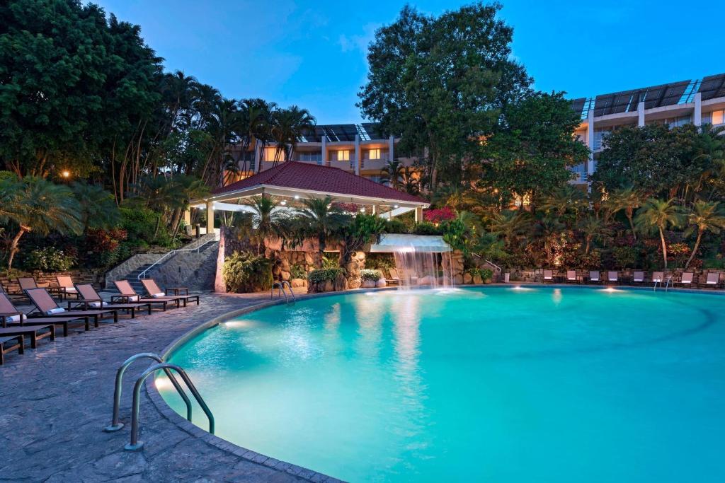 圣萨尔瓦多圣萨尔瓦多喜来登总统酒店的一座带椅子的大型游泳池和一座建筑