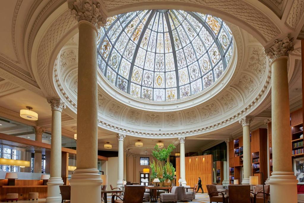 伦敦万豪斯莱德尼德勒斯精选纪念酒店的图书馆拥有玻璃圆顶天花板,配有桌椅