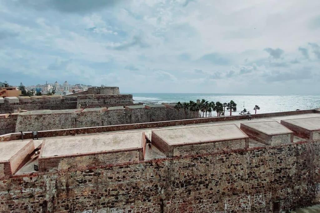 休达Acogedor piso cerca de la playa的一座古老的砖墙,背靠大海
