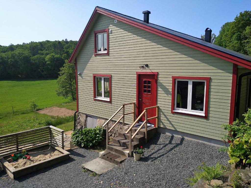VeddigeVilla Ulvatorp nära Varberg och Ullared的一座绿色的小房子,设有红色的门和楼梯