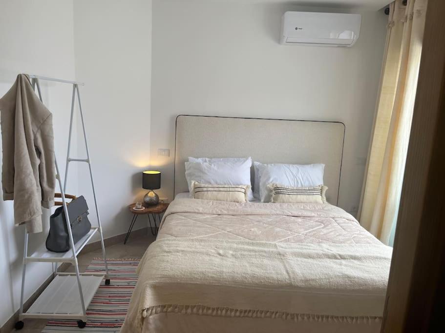 北哈马默特Appartement avec piscine et 10 min plage的一间卧室配有一张大床和衣架