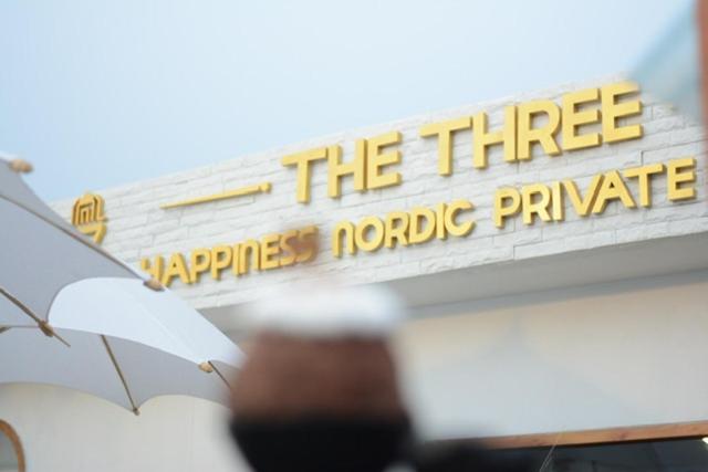 那空拍侬府The3 Happiness Nordic Private Home的建筑一侧的标牌,上面有雨伞