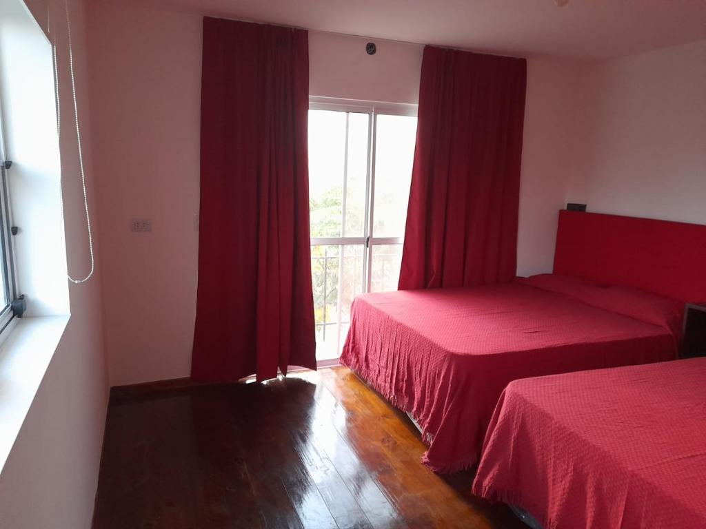 图蓬加托火山Mirador de Estrellas的一间卧室设有两张床,窗户配有红色窗帘