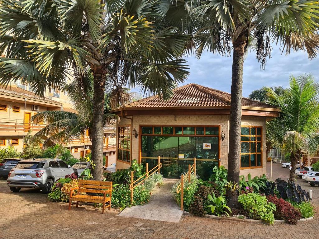 里贝朗普雷托Hotel Pousada Santa Rita的一座棕榈树建筑,前面设有长凳