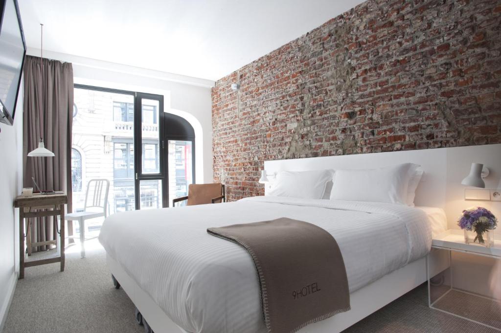 布鲁塞尔中央9号酒店的一间卧室设有一张大床和砖墙