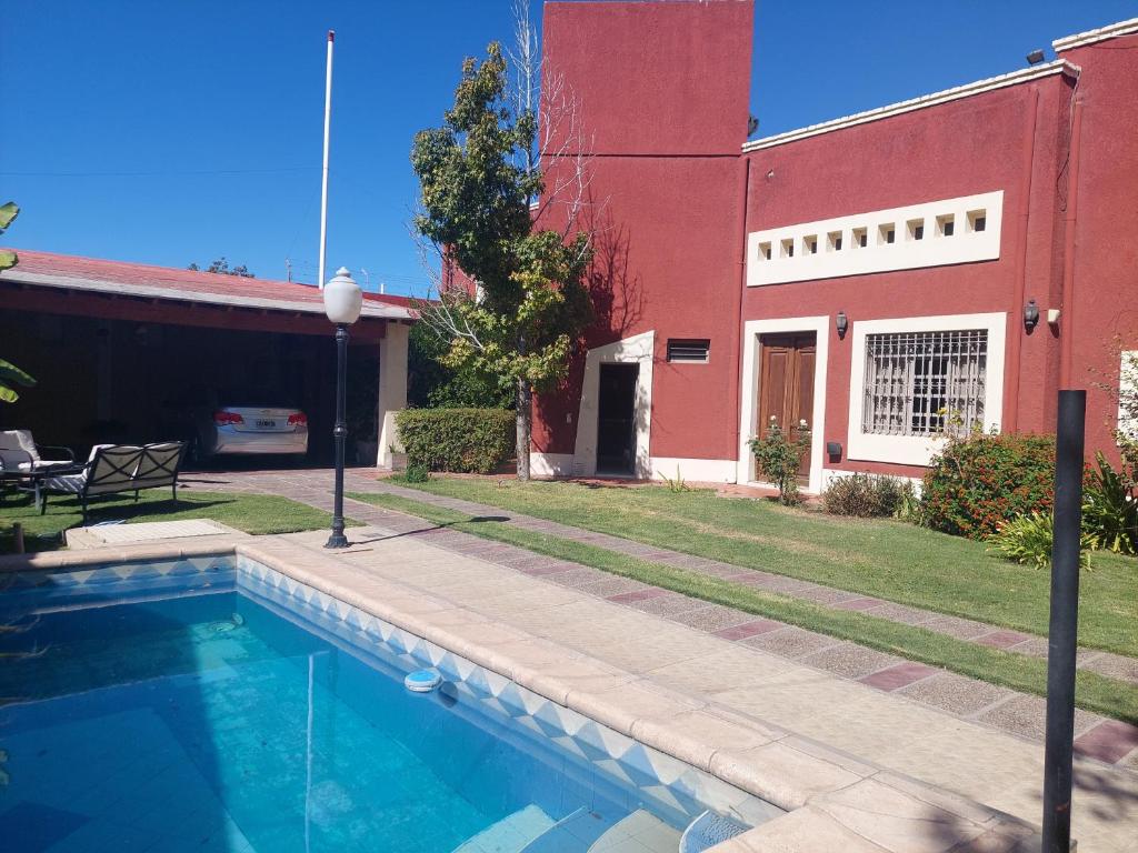 圣马丁Habitación con baño privado y estacionamiento的一座红色建筑前的游泳池