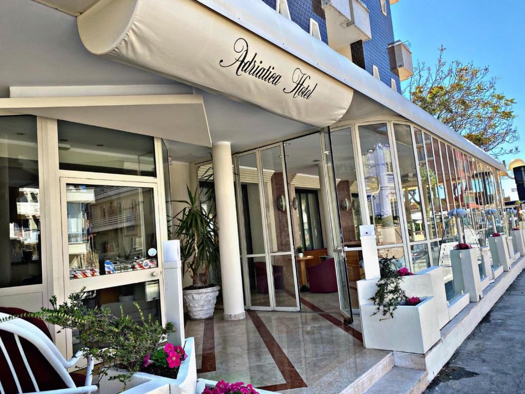 里米尼Hotel Adriatica sul Mare的建筑前方的商店,有窗户和植物