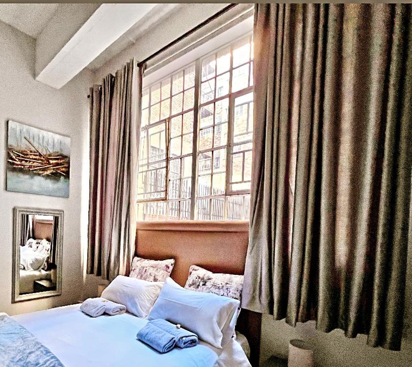 约翰内斯堡Mocha Apartment next to Maboneng的一间卧室设有一张床和一个大窗户