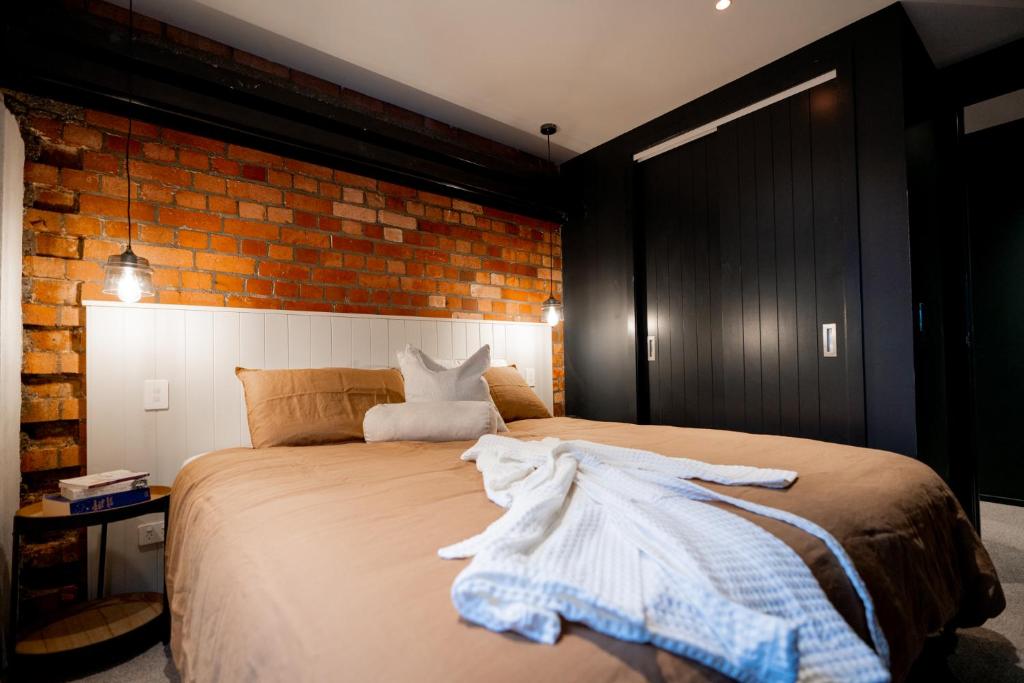 惠灵顿The Cobbler Hotel的一间卧室设有一张床和砖墙