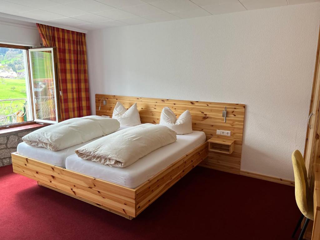 格洛特尔塔尔Gasthaus Pension Eicherg的卧室配有带枕头的木床和窗户。