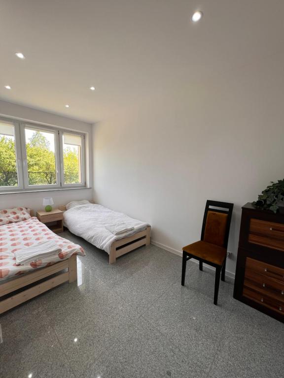 斯卡日斯科-卡缅纳Noclegi - Pokoje - STEMPO的一间卧室配有两张床、椅子和梳妆台