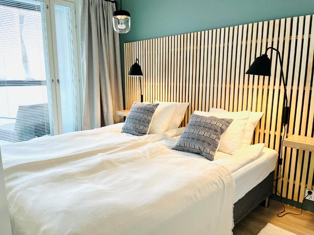 坦佩雷Uusi upea kaksio Tampereen ytimessä, pysäköinti, iso lasitettu parveke的卧室配有一张带两个枕头的大白色床