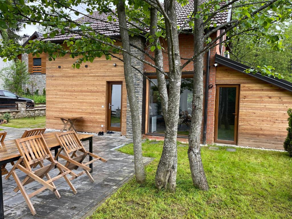 布雷佐维察Villa Alpina Brezovice的庭院设有2个木长椅和1座房子