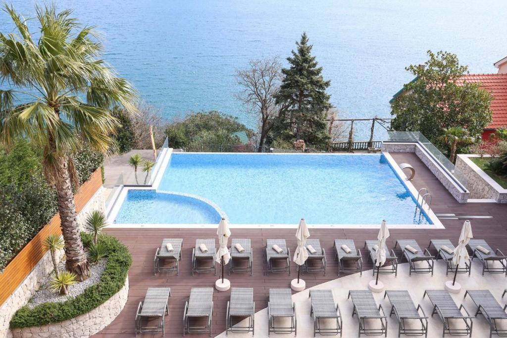 科托尔Bellezza Resort & SPA的一个带椅子的游泳池,背景是大海