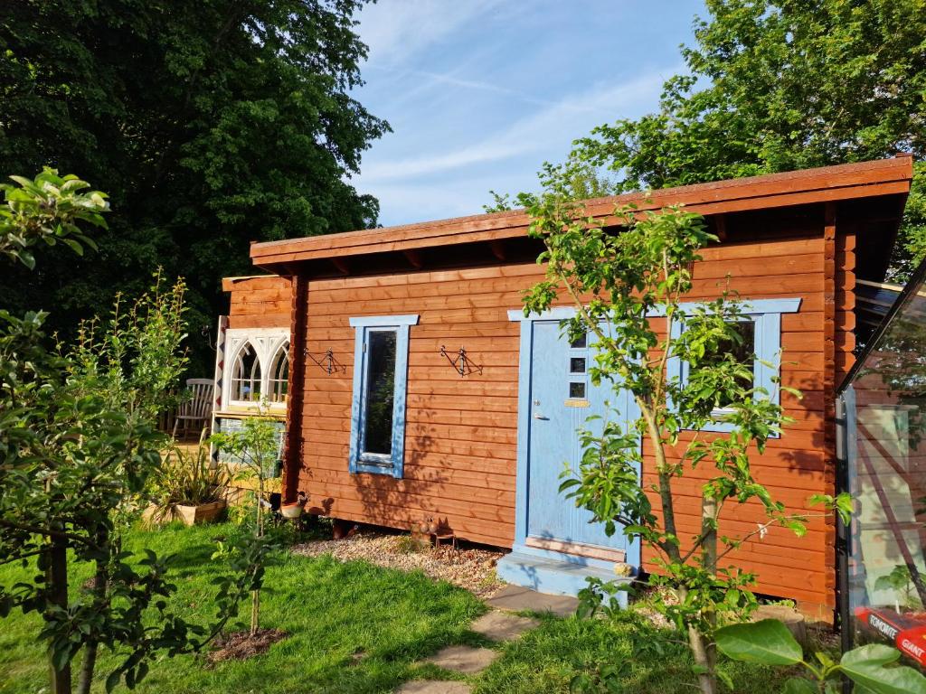 多切斯特Piddle Puddle Cabin的一个小木棚,有一扇蓝色的门