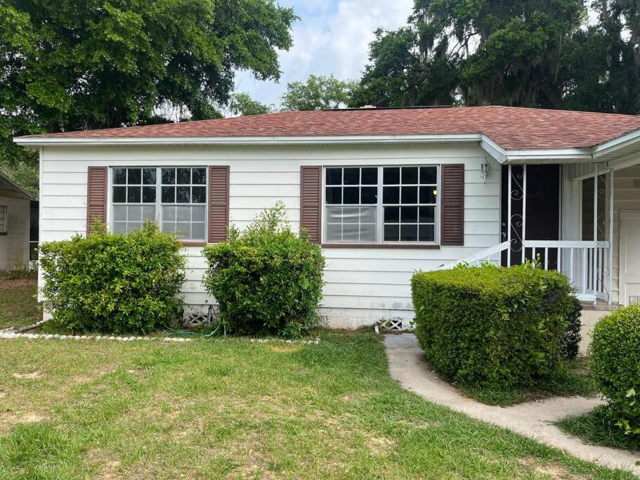 EustisMid Century Style Cottage Near Historic Downtown的前面有灌木丛的白色房子