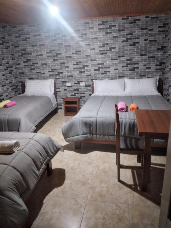泰斯Boutique Legata的一间卧室设有两张床、一张桌子和砖墙