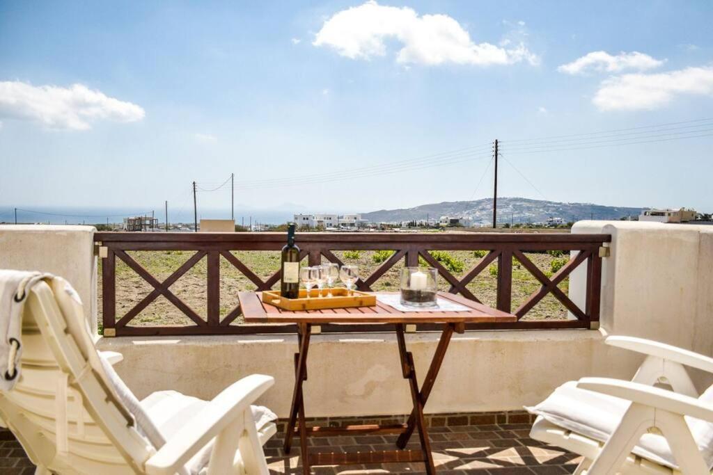 梅加洛克里Το Μεγάλο Αμπέλι的阳台上的桌椅和一瓶葡萄酒