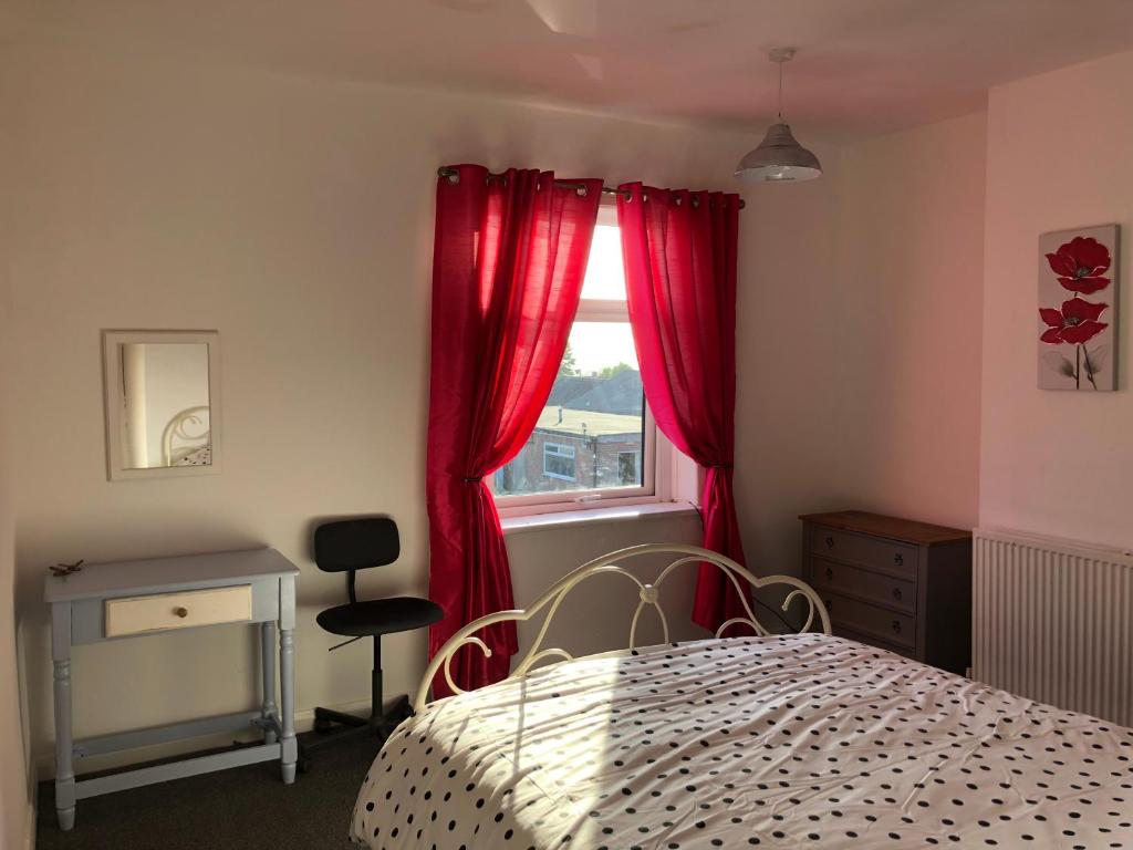 RenishawHilltop Cottage的一间卧室配有床和红色窗帘的窗户