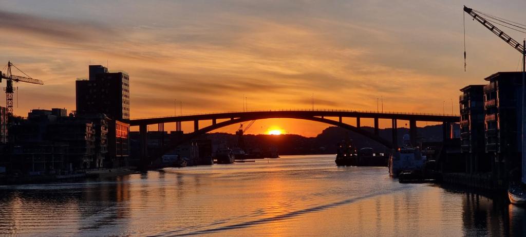 卑尔根Byleilighet i sjøkanten m terrasse的一座河上的桥梁,背面是日落