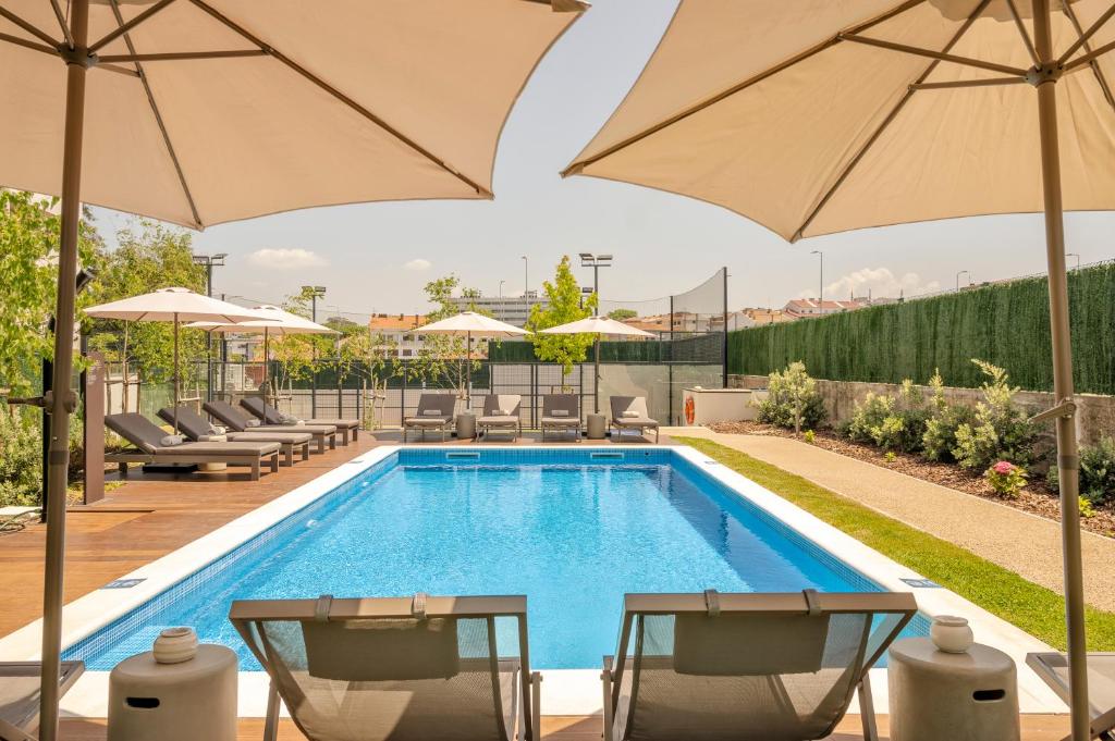 波尔图BFRESH Hotel - Padel, Pool & Fitness - Adults Only的游泳池旁的游泳池配有椅子和遮阳伞