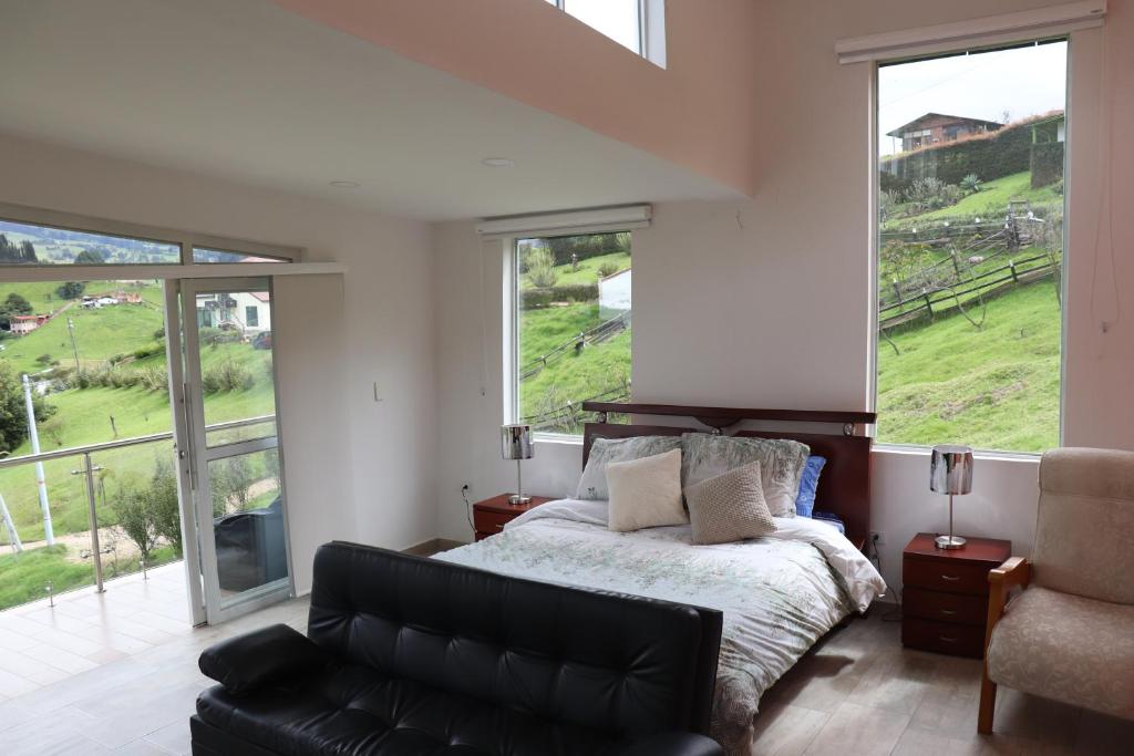 CoguaGlamping en Granja Campo Hermoso的一间卧室配有一张床、一张沙发和窗户。