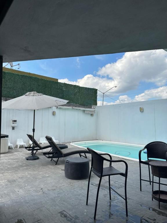 蒙特雷Residencia en Apodaca Nuevo León的一个带椅子和遮阳伞的庭院和一个游泳池