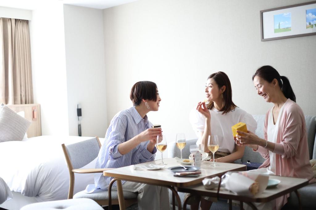 札幌札幌克罗斯酒店的一群坐在桌子旁看手机的人