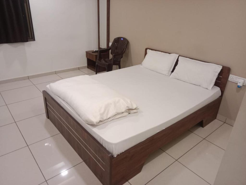 甘地讷格尔Hotel Shreeji's的一张带白色床单的床和一把椅子