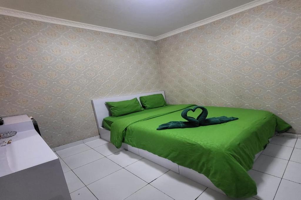 TekoB Nature Aeropolis Inn的一间卧室配有一张带黑色丝带的绿色床