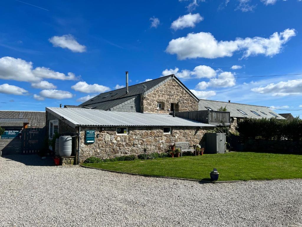 森嫩Lands End Hostel and B&B的一座石头建筑,旁边设有日光浴室