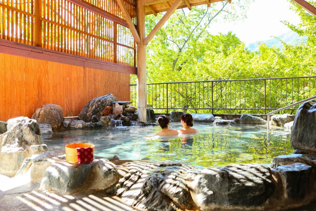 日光Ooedo Onsen Monogatari Hotel Kinugawa Gyoen的两人在后院的热水浴缸中