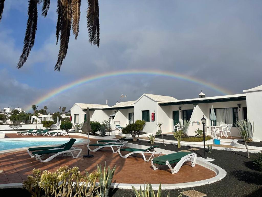 蒂亚斯Bungalows Doble UVE的天空中的彩虹,在一座带游泳池的房子上