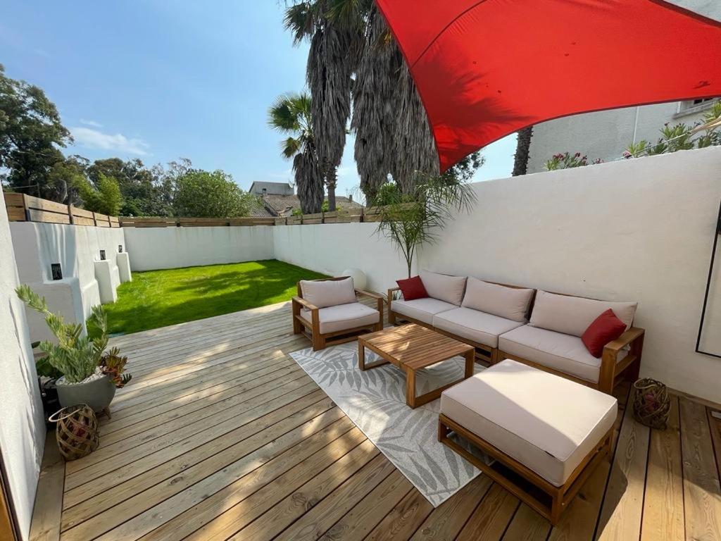 卢恰纳Mini Villa Indépendante à 350m de la mer (LAX)的一个带沙发和红伞的庭院