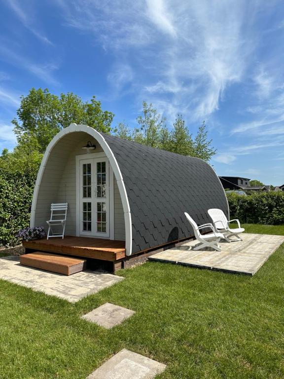 Belt-SchutslootLODGE, een super knus tiny house, nabij vaarwater en haven!的草顶状的房子,有两把椅子