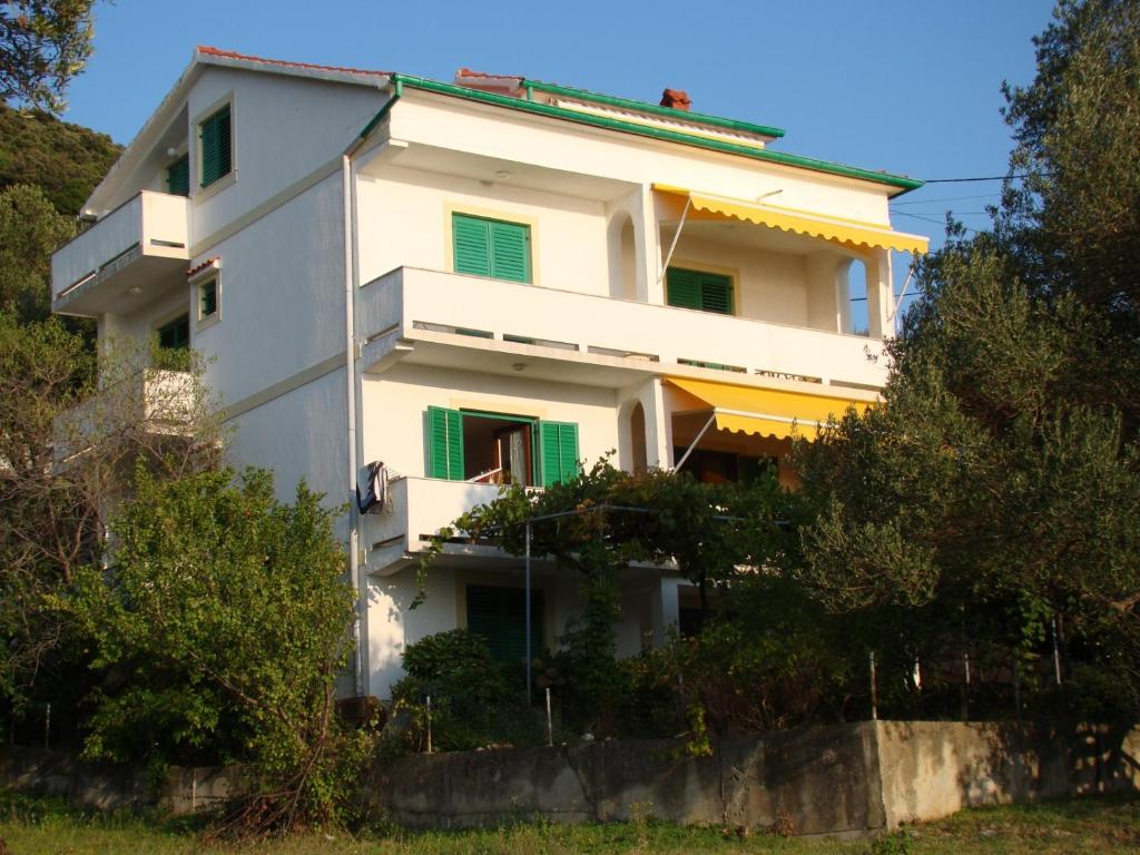 苏佩塔斯卡德拉加Apartment in Supetarska Draga with sea view, terrace, air conditioning, WiFi 4552-8的白色的建筑,上面有绿色百叶窗