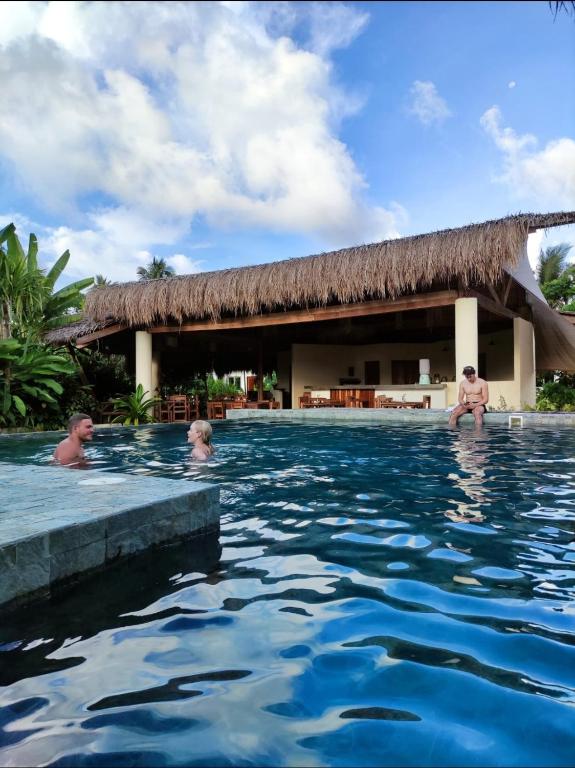 卢纳将军城Tropical Bungalows-Siargao的一群人在度假村的游泳池里