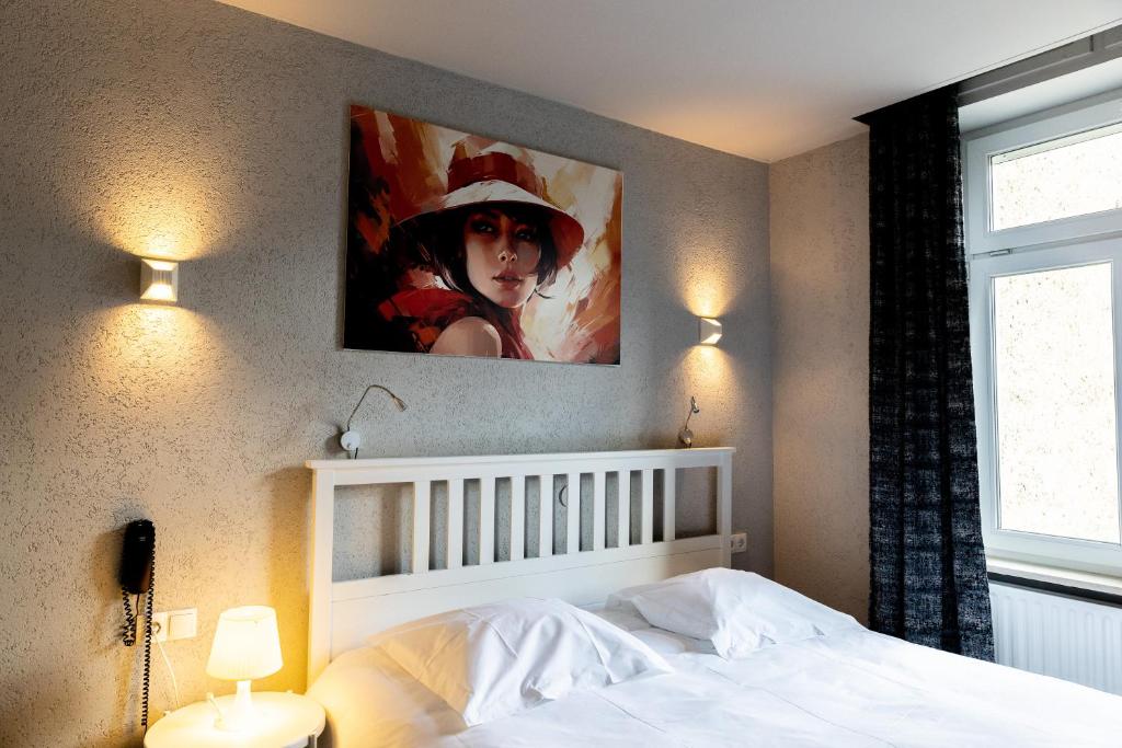 卢森堡布里斯托酒店的卧室配有一张白色床,墙上挂有绘画作品