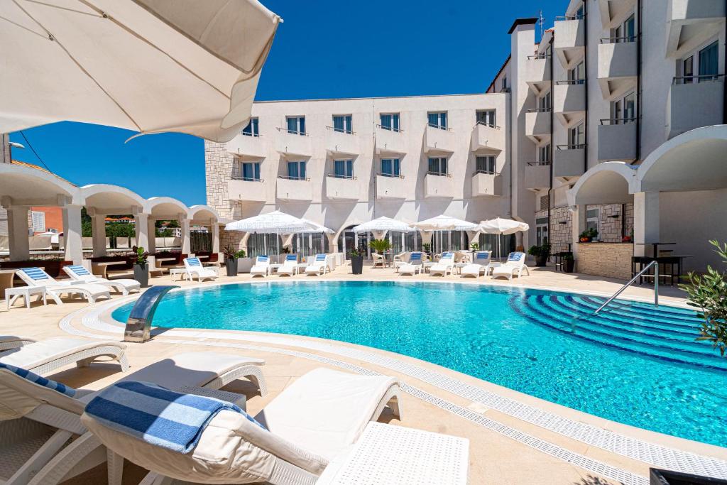 尼亚卢卡科尔奇拉酒店的一座带椅子和遮阳伞的游泳池位于一座建筑旁边