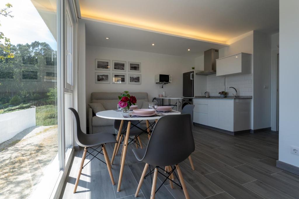 科尔库维翁Solpor Galitrips - Apartamentos Corcubión的厨房以及带桌椅的起居室。