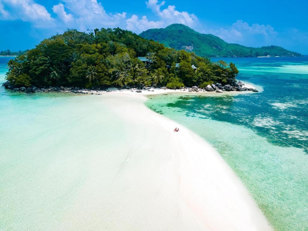 Round IslandJA Enchanted Island Resort Seychelles的和海滩上的人一起在海洋中的岛屿