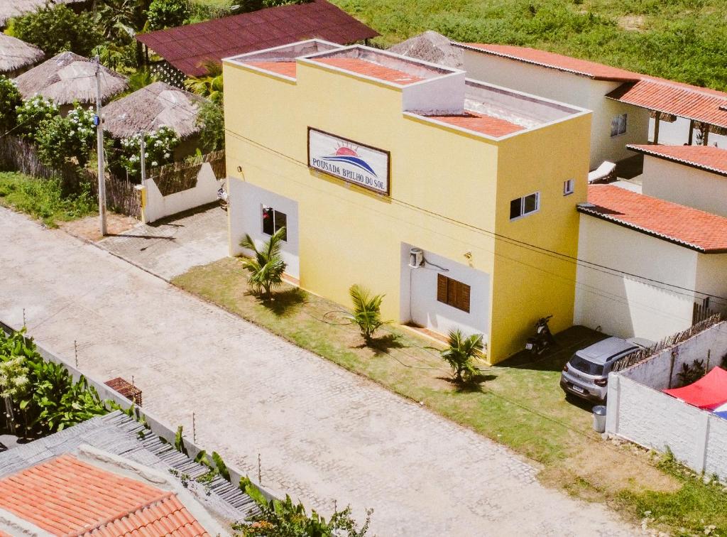 圣米格尔-杜戈斯托苏Pousada Brilho do Sol的棕榈树黄色房子的顶部景色