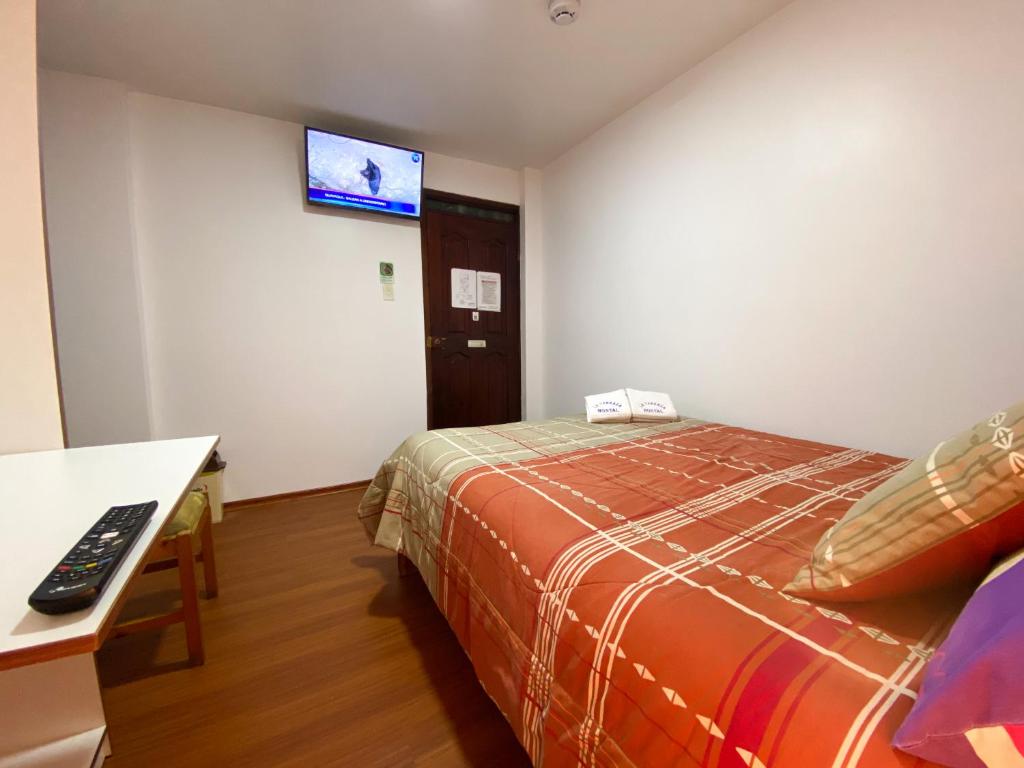 基多Hostal La Terraza的酒店客房设有一张床和墙上的电视