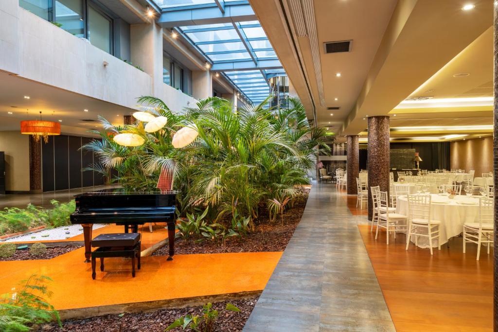 奥维多Iberik Santo Domingo Plaza Hotel的餐厅的三角钢琴,配有桌椅