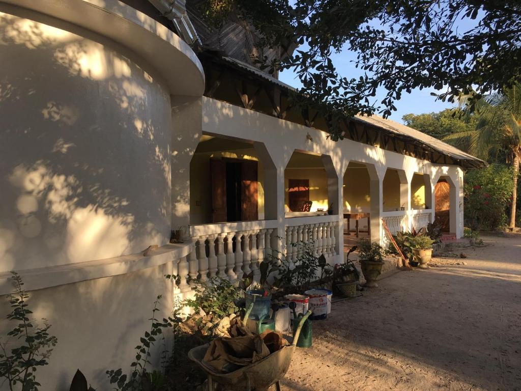 KafountineKaramba Lodge的白色的建筑,有门廊和一些植物