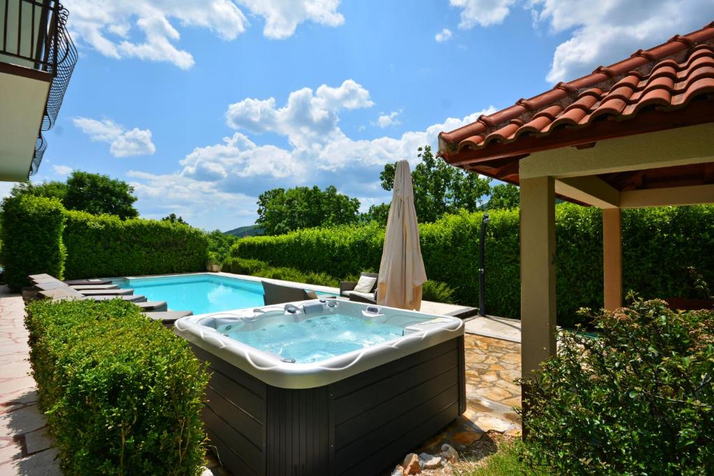 特里尔Villa Bisko with heated pool & jacuzzi的庭院内的热水浴池,配有遮阳伞